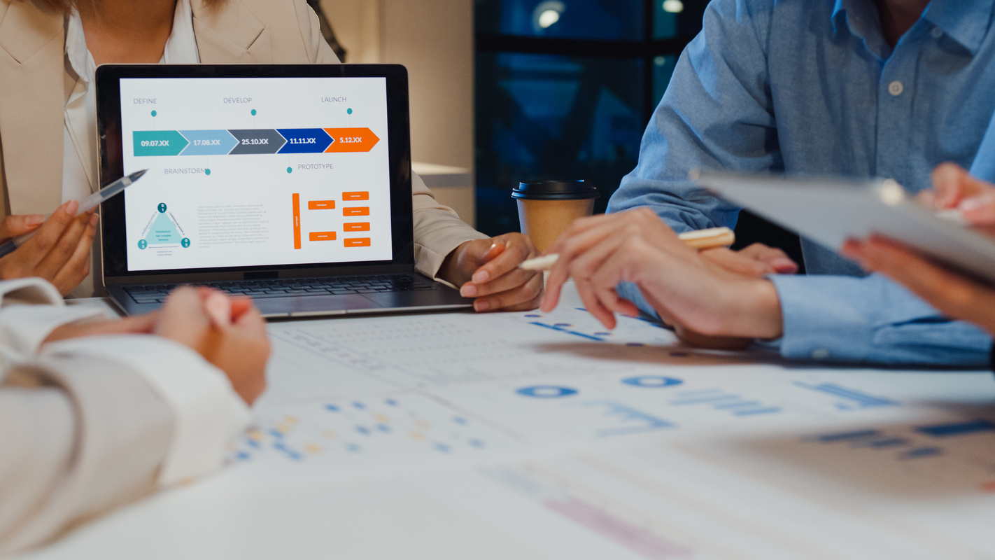 Closeup asia businesspeople meeting plan analysis statistics brainstorm and header of team hold laptop point graph chart and employee take note at home office night. Finance strategy success concept.