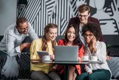 multiethnic group of friends lookign at laptop in cafe